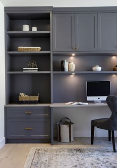 a home office with gray cabinets and a white rug in front of the computer desk