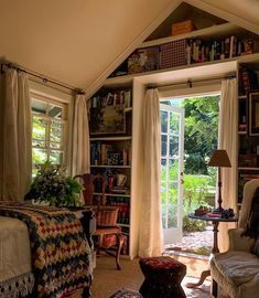 a living room filled with furniture and bookshelves next to an open door that leads to a patio