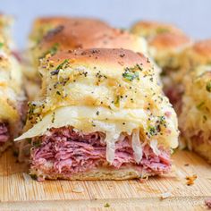 a sandwich cut in half sitting on top of a wooden cutting board with cheese and meat