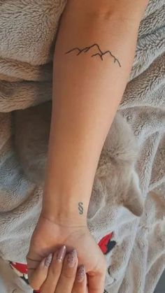 a woman with a tattoo on her arm holding the hand of another person's wrist