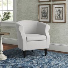 a white chair sitting on top of a blue rug in a living room next to a window