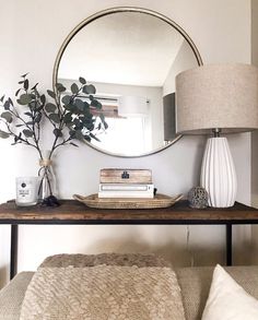 a living room with a couch, table and mirror on the wall next to it