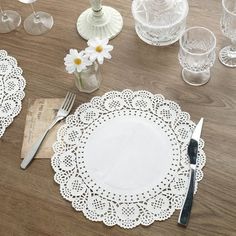 the table is set with white doily and silverware