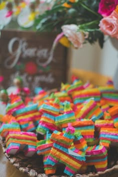 colorful candies are in a bowl on a table with flowers and signs behind them