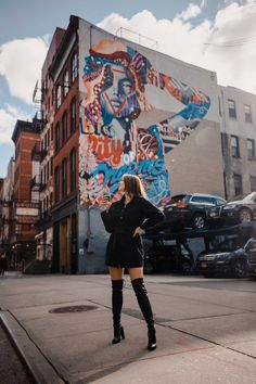 a woman standing on the sidewalk in front of a building