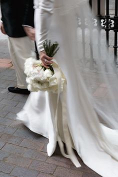 the bride and groom are walking down the street