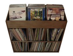 a wooden shelf filled with lots of different types of records and cds on top of each other