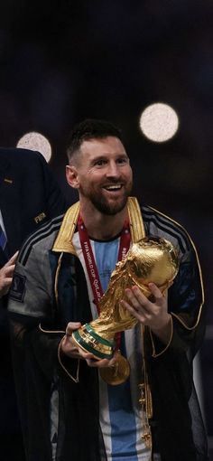 a man holding a soccer ball in his hand and wearing a gold trophy around his neck