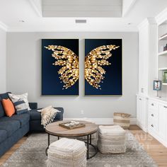 two paintings on the wall above a coffee table in a living room with blue couches