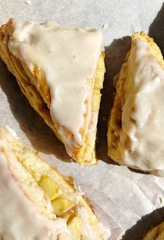 three pastries with icing sitting on top of paper