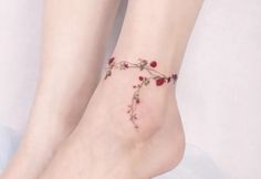 a woman's bare foot with red flowers on the bottom of her ankles and an ankle tattoo