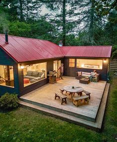 a small cabin in the woods with a deck and picnic table