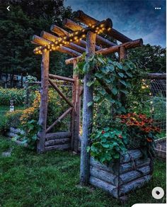 an outdoor garden with plants and lights on the arbor, in front of a fence