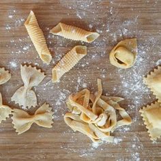 several different types of pasta on a wooden table covered in powdered sugar and flour