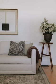 a living room with a couch, table and potted plant