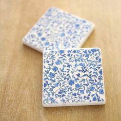 two blue and white tiles sitting on top of a wooden table