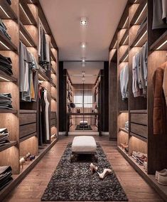 a walk in closet with lots of clothes on shelves