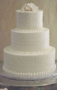 a three tiered white wedding cake sitting on top of a table