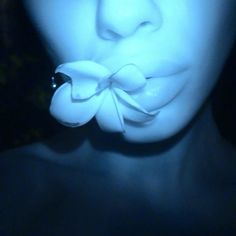 a close up of a person with a flower in their mouth and the light on her face