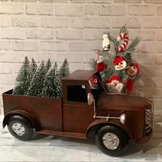 an old fashioned truck with a christmas tree in the back and stuffed animals on top