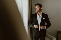 a man in a suit standing next to a window