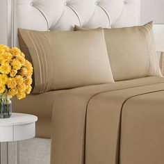 a bed with yellow flowers in a vase on top of it