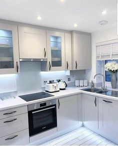 a kitchen with white cabinets and stainless steel appliances in the center, along with a vase filled with flowers on the counter