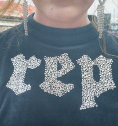 a close up of a person wearing earrings and a t - shirt with the word r & b on it