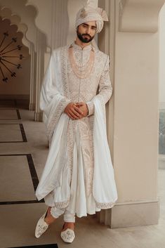 a man in a white outfit standing next to a pillar