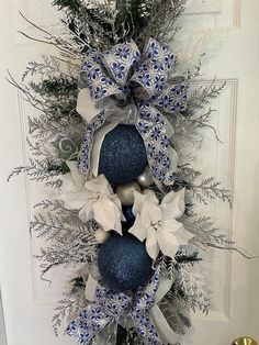 a blue and white christmas ornament hanging on the front door with silver ornaments