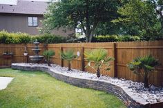 a fenced in yard with plants and rocks