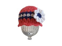 a red, white and blue crocheted hat sitting on top of a glass vase