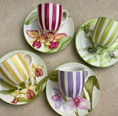 four colorful cups and saucers with flowers painted on them