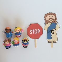 a group of toy figurines sitting on top of a white wall next to a stop sign