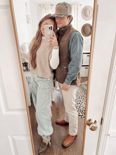 a man and woman standing in front of a mirror taking a selfie with their cell phone