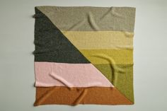 a multicolored blanket laying on top of a white table next to a wall