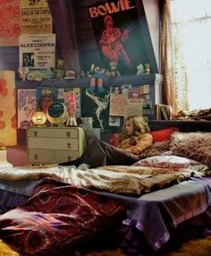 a woman is laying on her bed in front of a window with posters above it