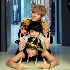 three young men are posing for the camera with their hands in the air while wearing hats