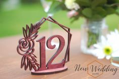 there is a small wooden house with the number twelve on it and flowers in the vase