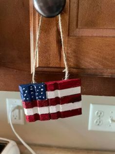 an american flag hanging from a hook on a kitchen cabinet door with a light switch in the background