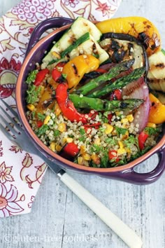 a purple bowl filled with vegetables on top of a table next to utensils