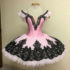 a pink and black ballerina dress sitting on top of a mannequin