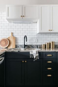 a kitchen with black cabinets and white subway backsplash, brass pulls on the cabinet doors