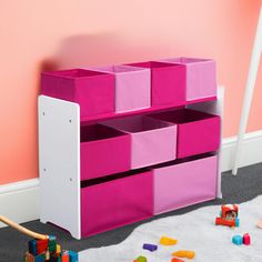 a child's toy storage unit with pink bins and toys on the floor