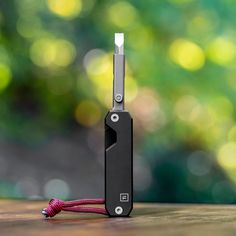 an electronic device connected to a cord on top of a wooden table with blurry trees in the background