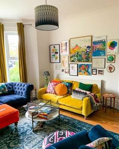 a living room filled with colorful furniture and pictures on the wall above it's windows