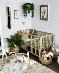 a baby crib in a white room with potted plants and other decorations on the wall