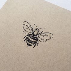 a drawing of a bee on top of a piece of brown paper with black ink