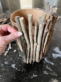 a person is holding up some sticks in a glass container on a table with other items