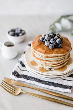 a stack of pancakes topped with blueberries and syrup